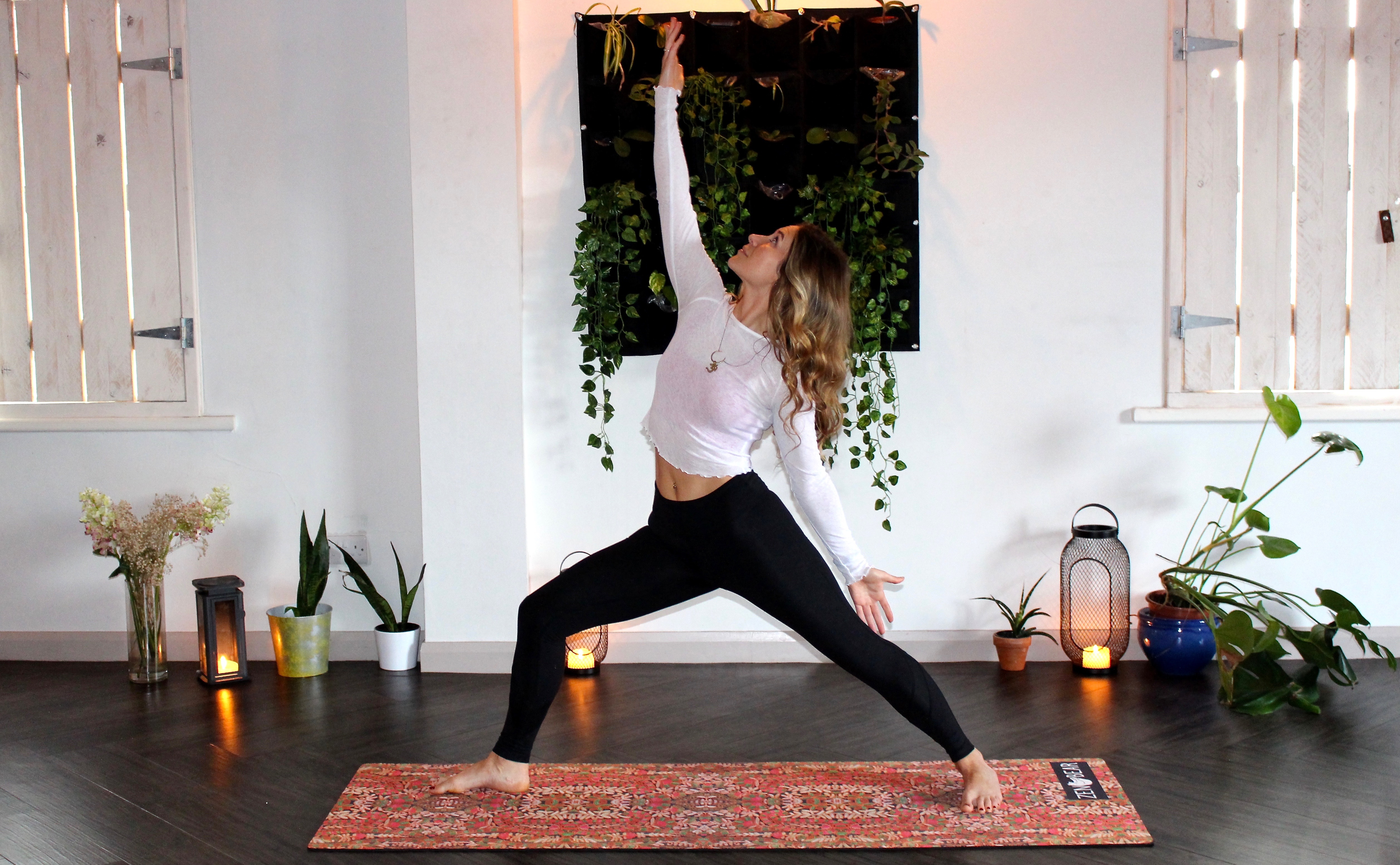 White woman practicing yoga surrounded by candles and plants